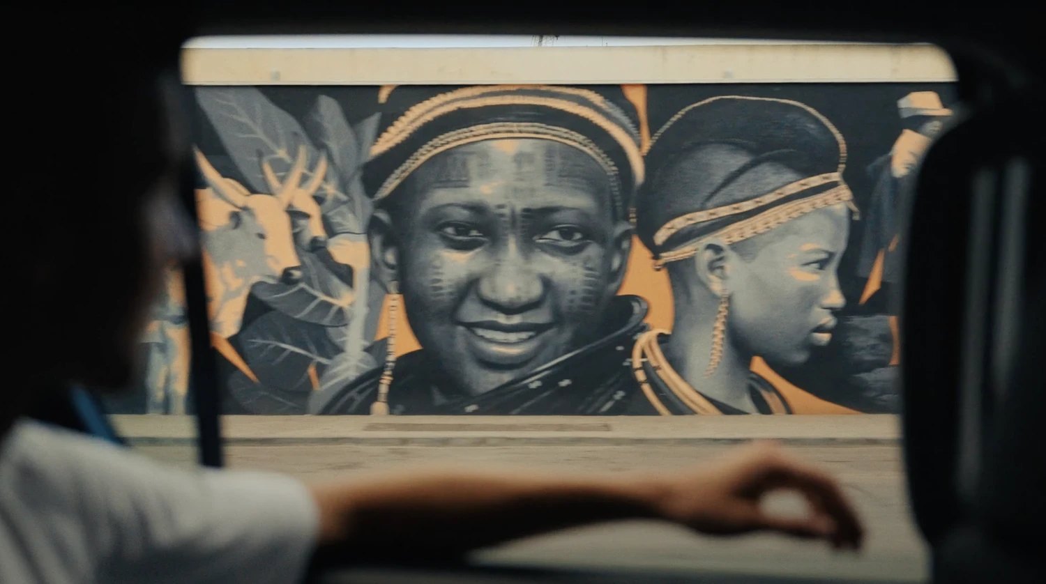 A mural of two faces with traditional scarification, seen from the car in Cotonou