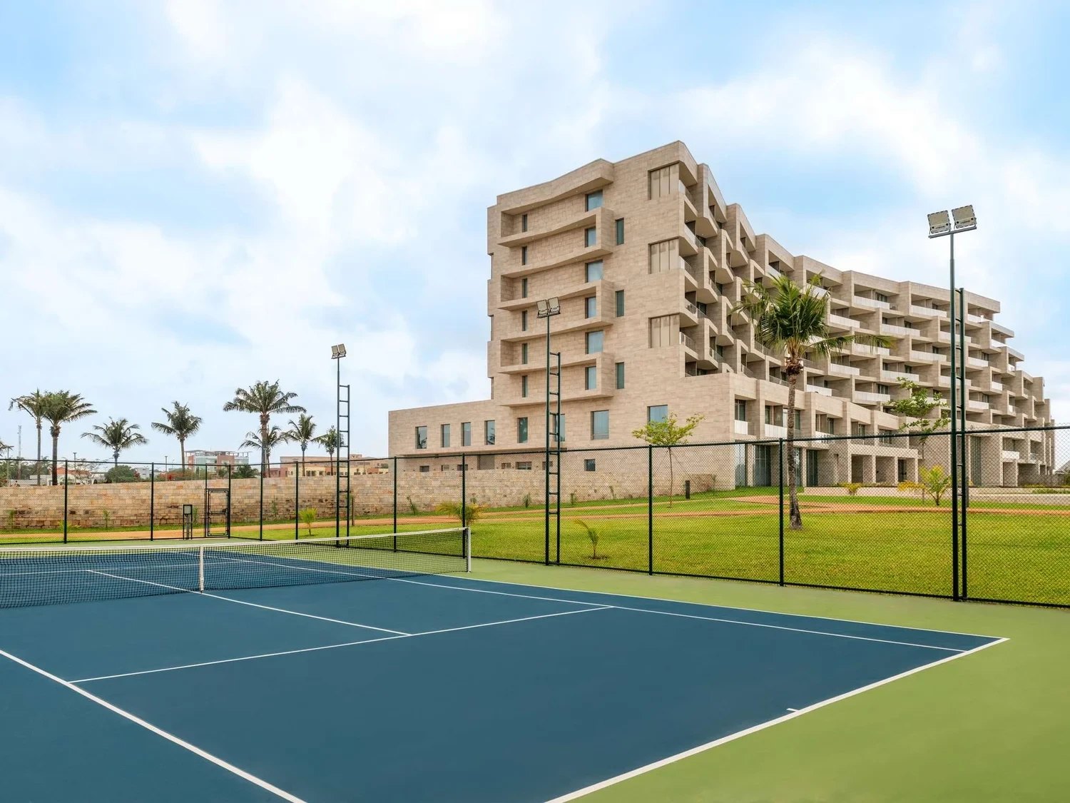 A tennis court in front of the hotel, palms behind